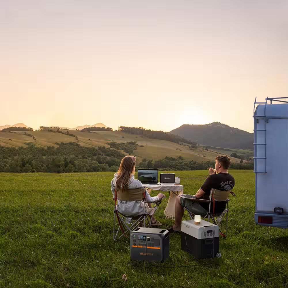 AC200PL Solar Superhero powering devices on a camping trip next to a van at sunset.