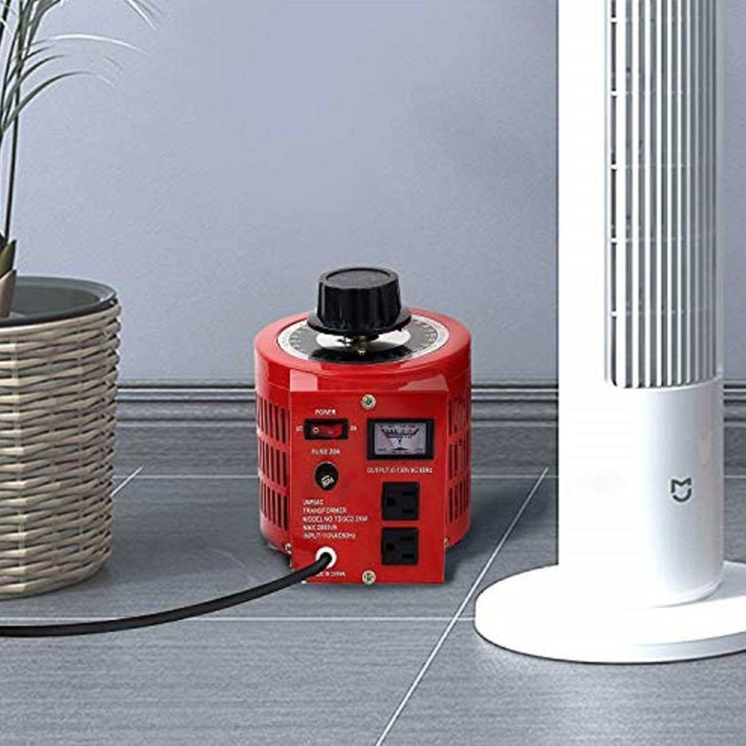 1000VA voltage party machine transformer next to a fan and potted plant on a tiled floor.